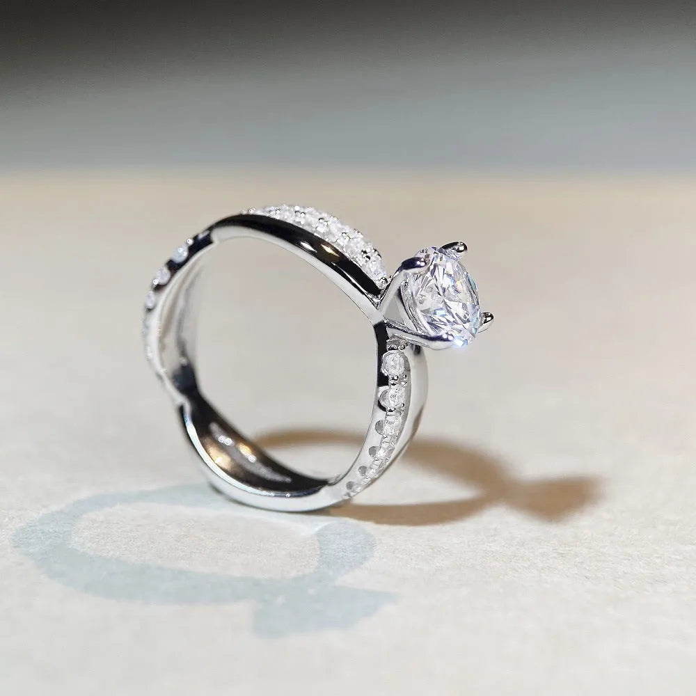 Silver ring with 1 karat moissanite in four-claw setting on a geometric twisted arm band.