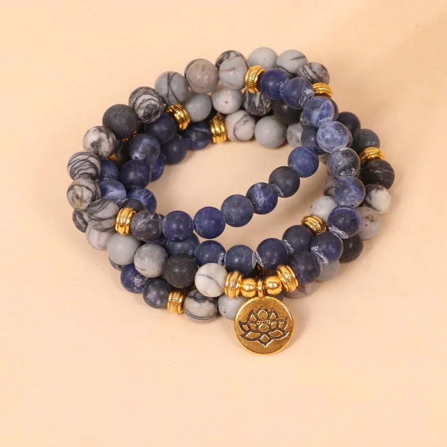 Blue multi-layer bracelet with patterned network stone beads and alloy components.