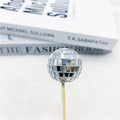 Glass disco ball cake decoration with wooden stick in various sizes on a cake