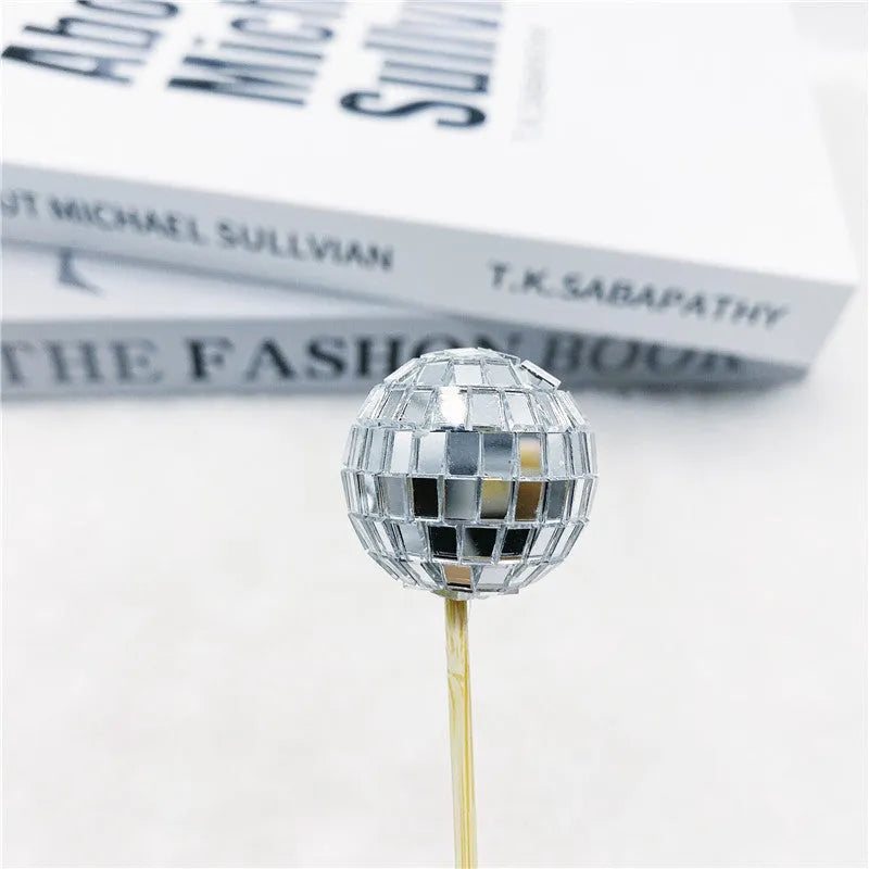 Glass disco ball cake decoration with wooden stick in various sizes on a cake
