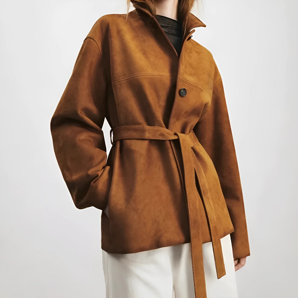 Yellow brown mid-length cashmere coat with a Peter Pan collar and leather stitching on a hanger.