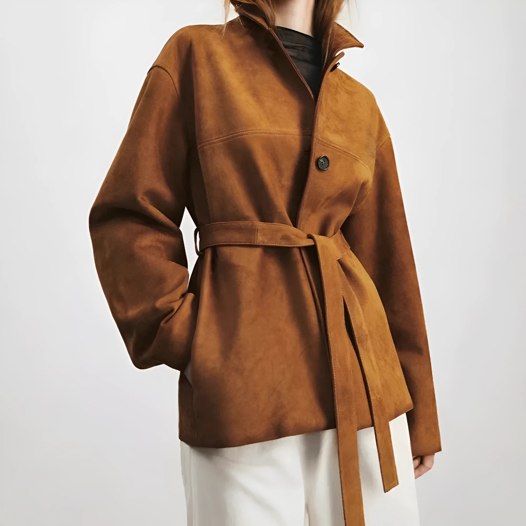 Yellow brown mid-length cashmere coat with a Peter Pan collar and leather stitching on a hanger.