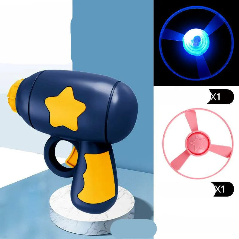 Blue plastic flying saucer launcher toy with LED-lit discs on a yellow target board.
