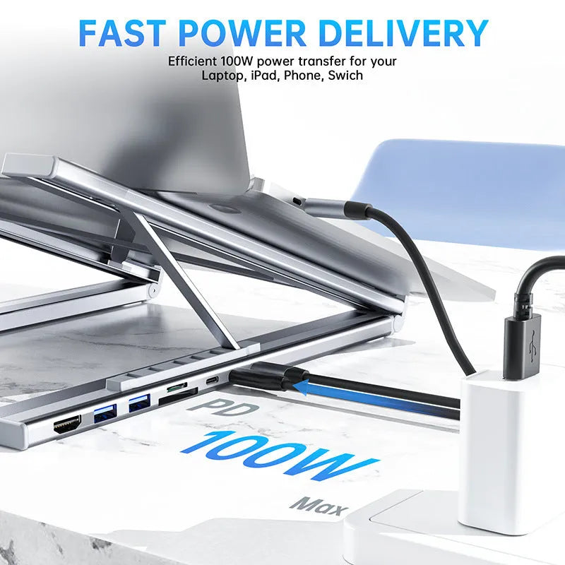 Silver aluminium folding laptop stand with integrated multi-port docking hub on a desk.