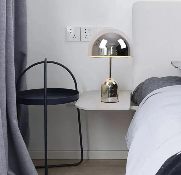 Mushroom-shaped table lamp with metal base in rose gold finish on wooden surface