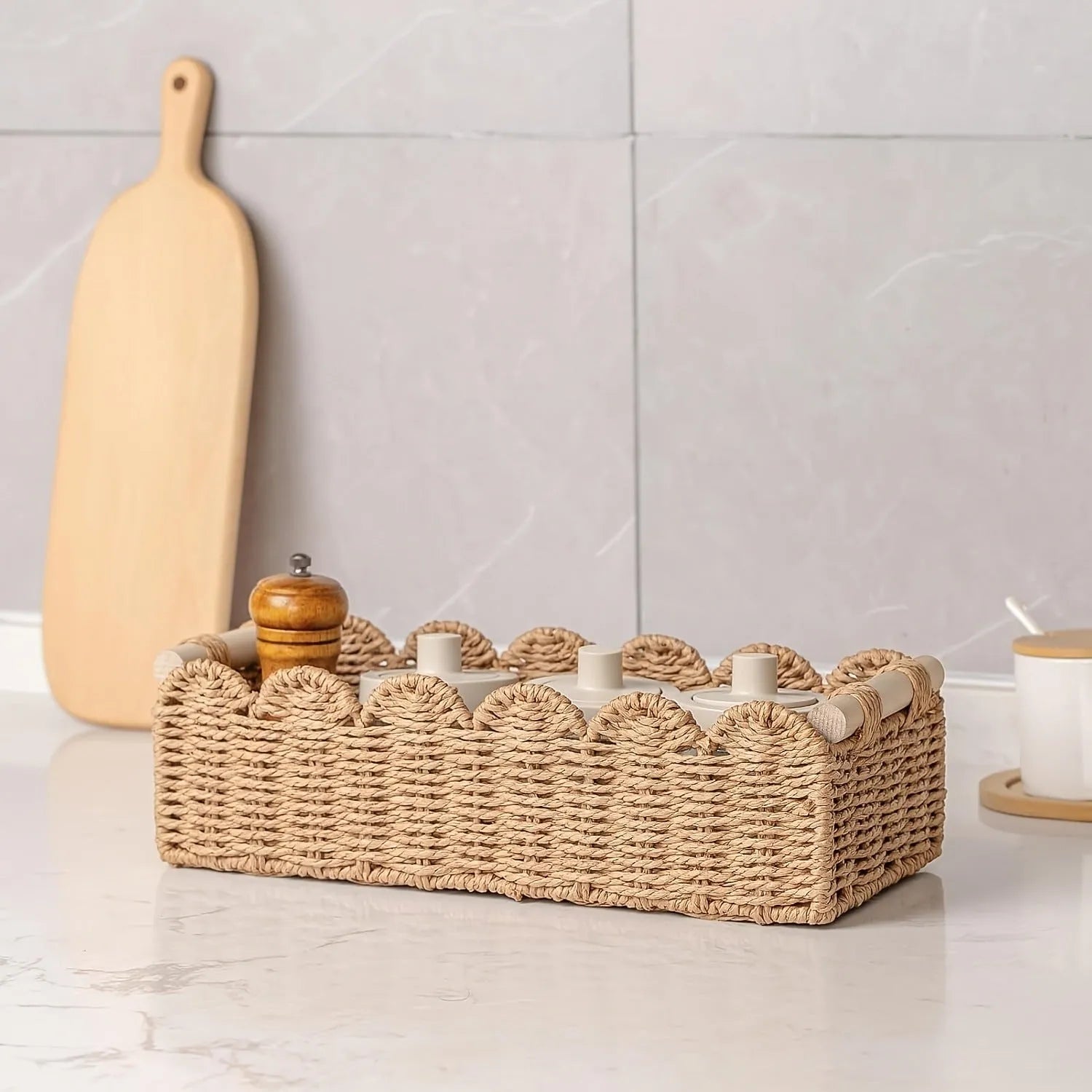 Modern minimalist woven paper storage basket on a desktop, holding remote controls and pens.