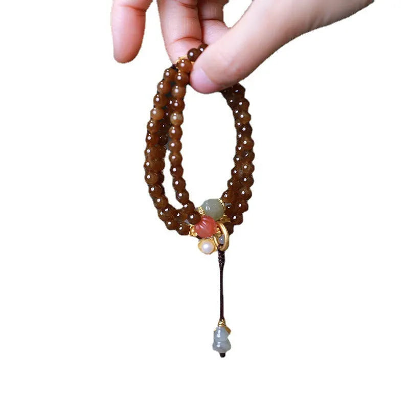 Brown Hetian Jade three-ring bracelet with butterfly and gourd charms on a wrist.