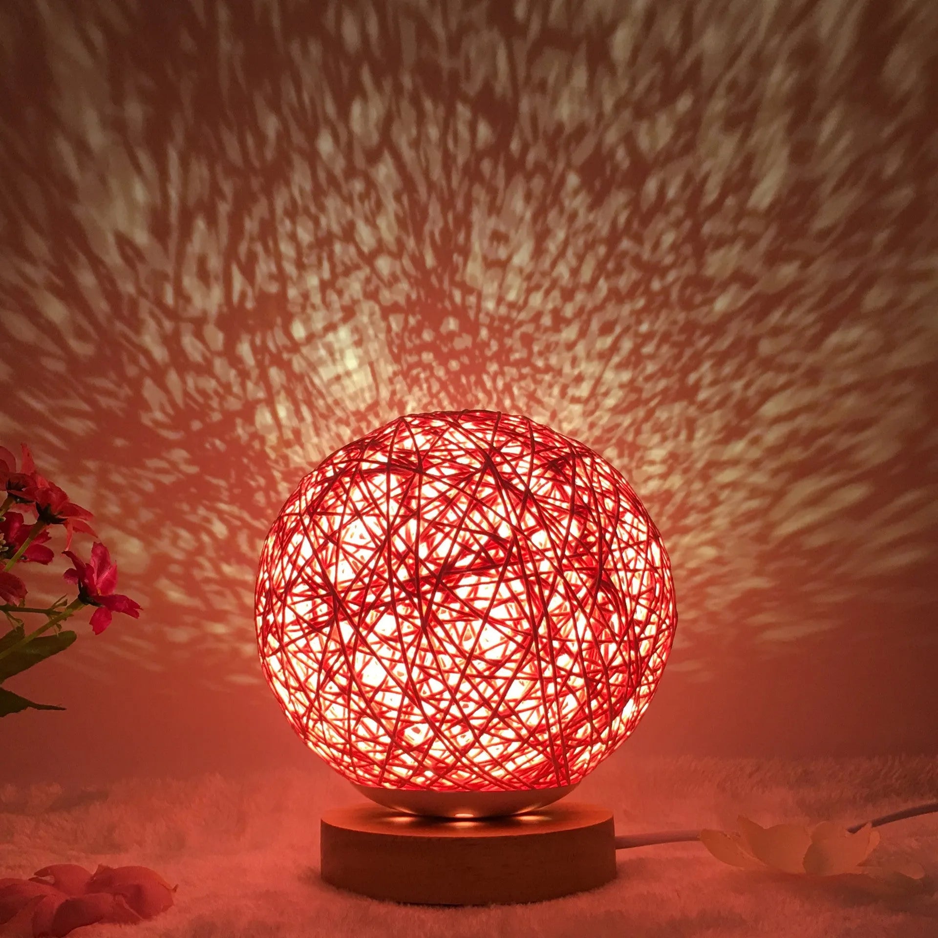 Rattan ball table lamp with woven shade and warm LED lighting on wooden surface