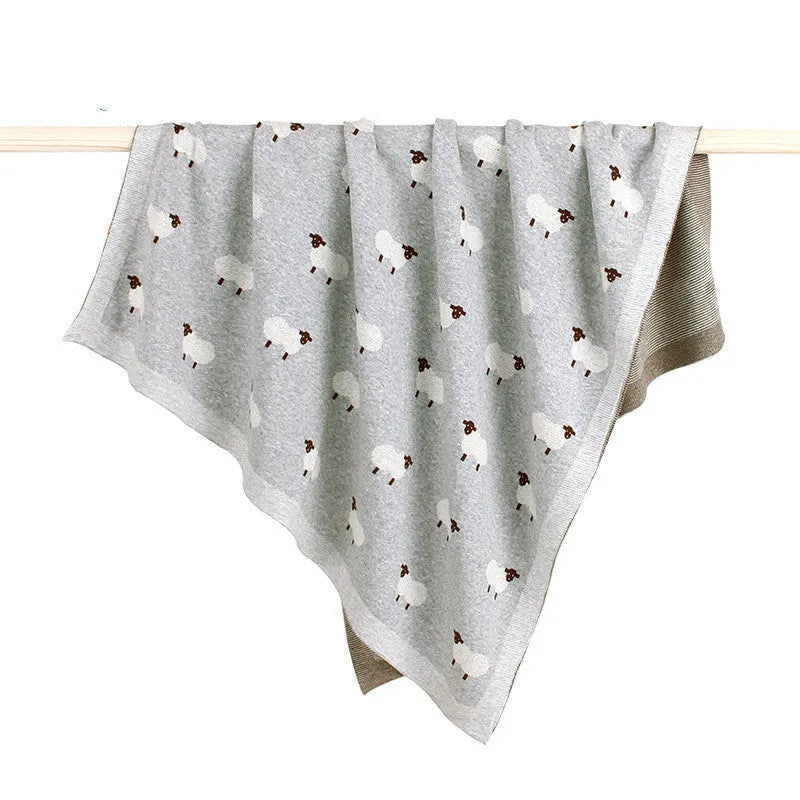 Grey 100% cotton baby blanket cover draped over a sheepskin rug in a pram.