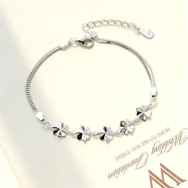 Silver four-leaf clover bracelet with adjustable chain on white background