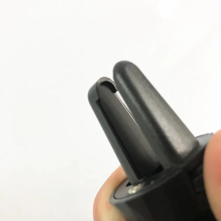 Matte black car phone holder clipped onto a car air vent, holding a smartphone.