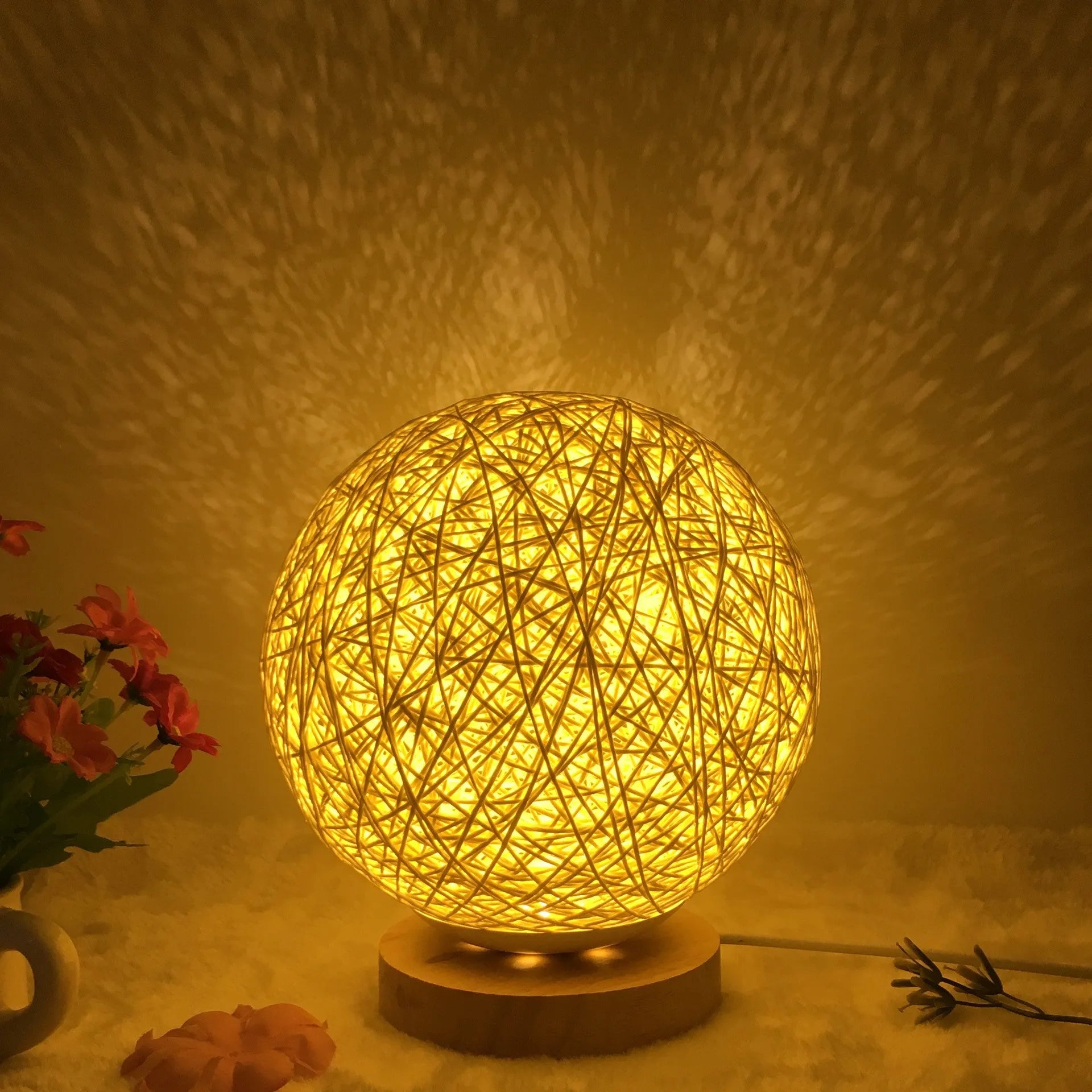 Rattan ball table lamp with woven shade and warm LED lighting on wooden surface