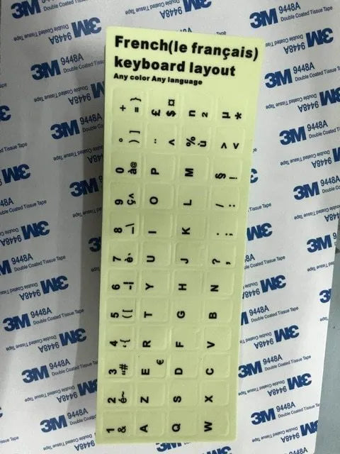 Glowing yellow multilingual keyboard stickers showing Arabic, Thai, Hebrew, French, Italian and German characters