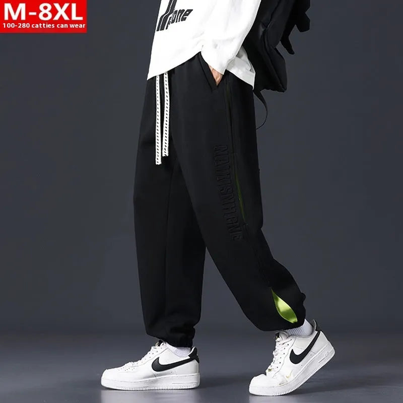 Man wearing loose-fit black trousers with printed stitching detail and a banded ankle cuff.