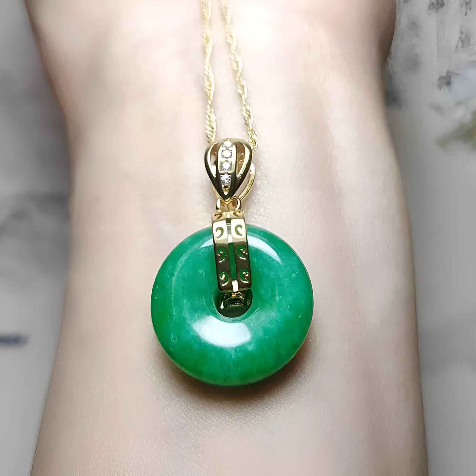 Vacuum electroplated emerald green jade pendant in safety buckle shape on white background