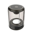 Transparent Bluetooth speaker with black housing and suction cup base on a glass table