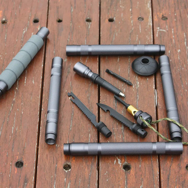 Dark grey aluminium trekking pole with tactical knife and screwdriver accessories on a hiking trail