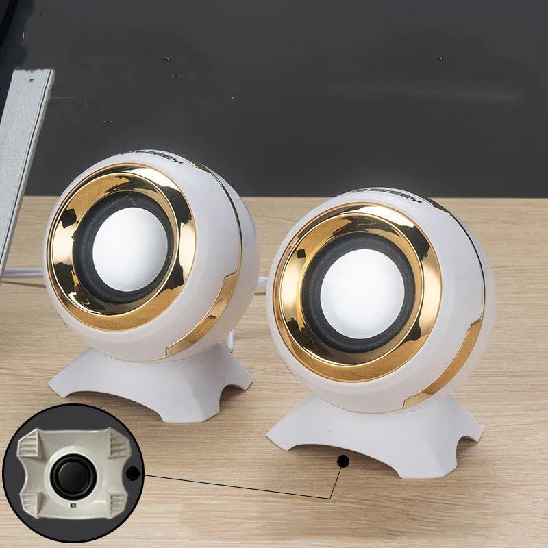 Black and gold USB-powered desktop computer speakers beside laptop showing compact 10cm dimensions