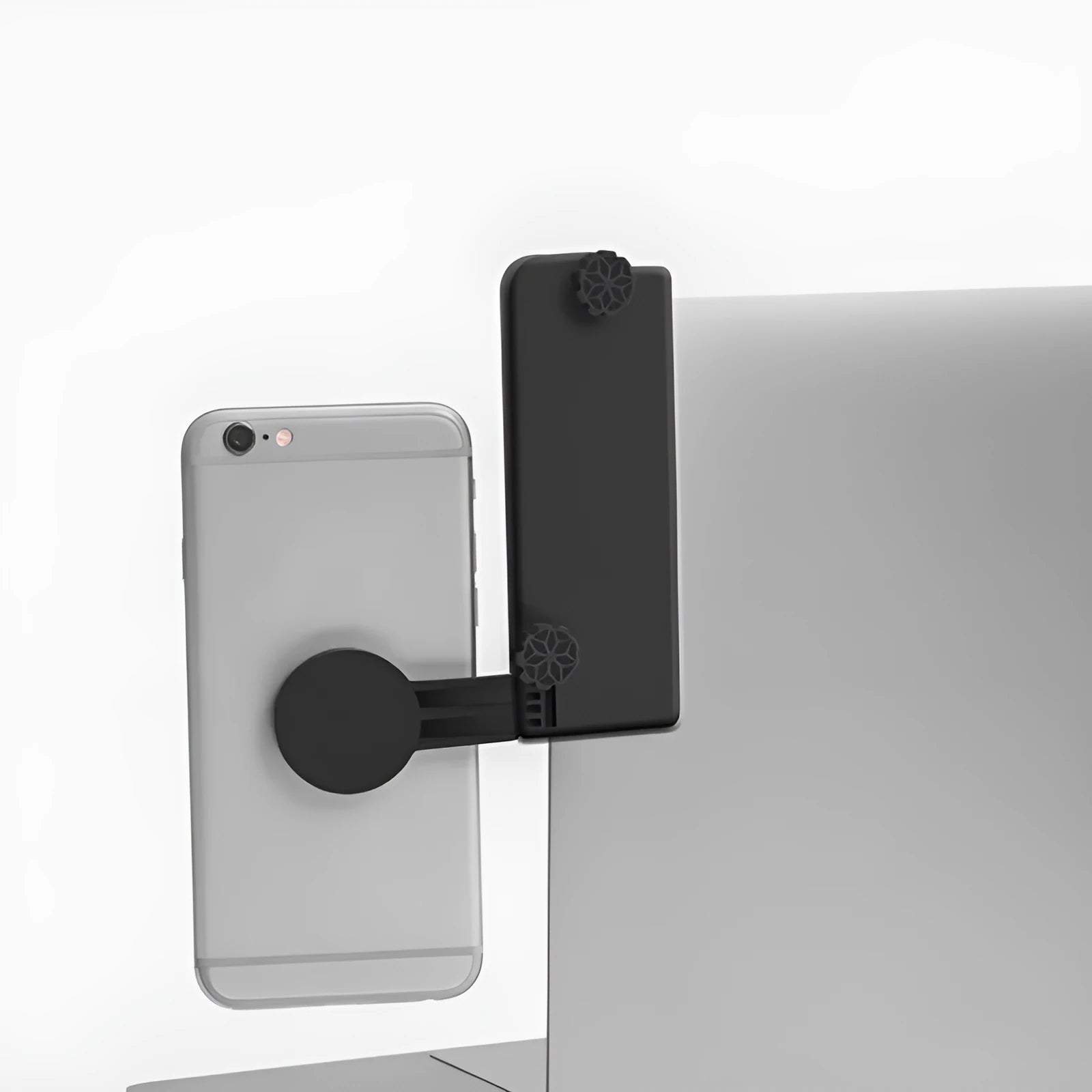 Black silicone computer side screen clip phone holder attached to a laptop, with a smartphone held magnetically