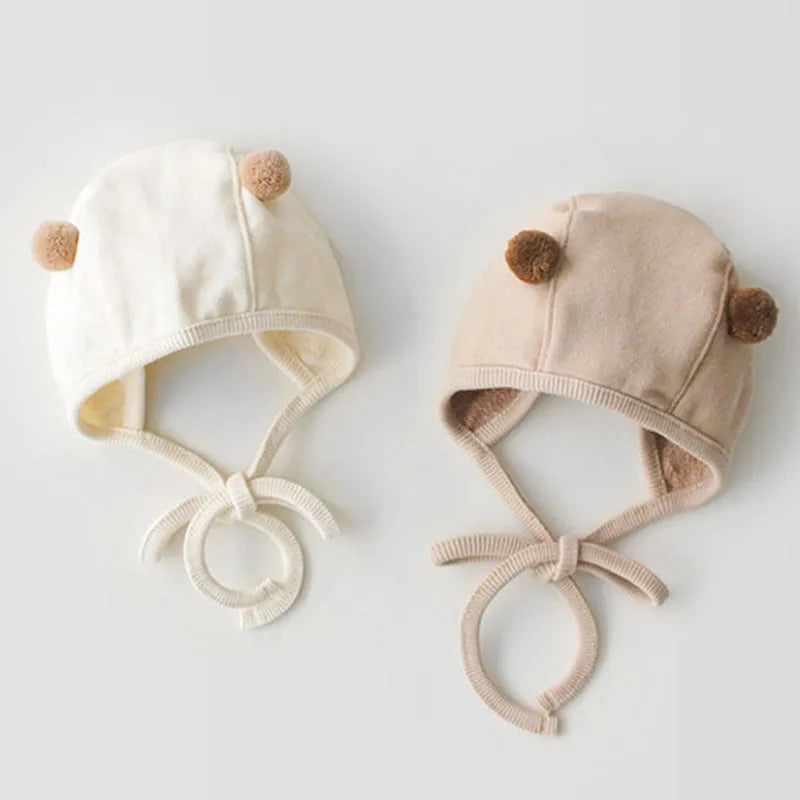 Baby sleeveless strapless cotton robe with detachable hood in brown or white on a plain background