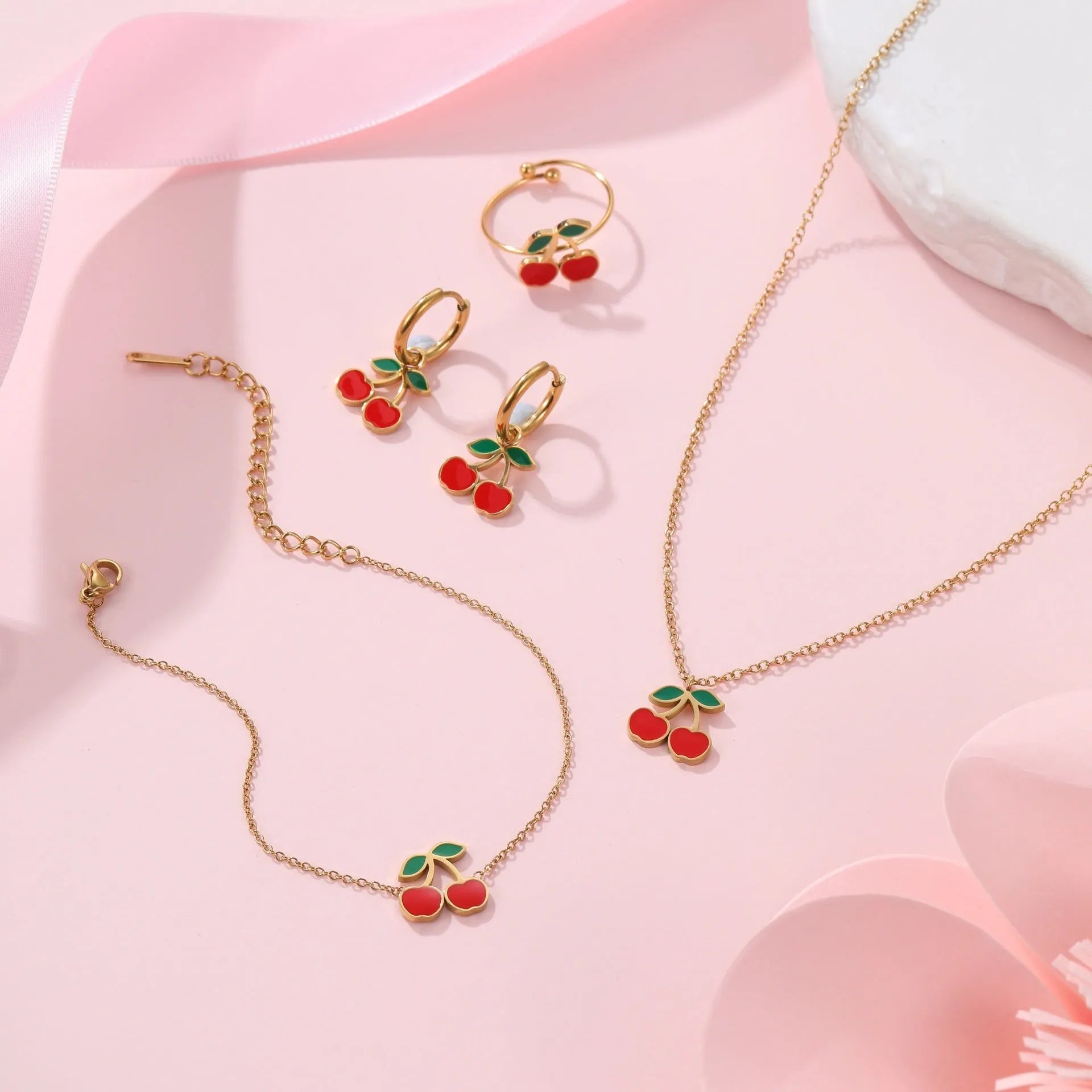Complete cherry jewellery set showing stainless steel necklace, bracelet, earrings, and ring with 18K electroplating
