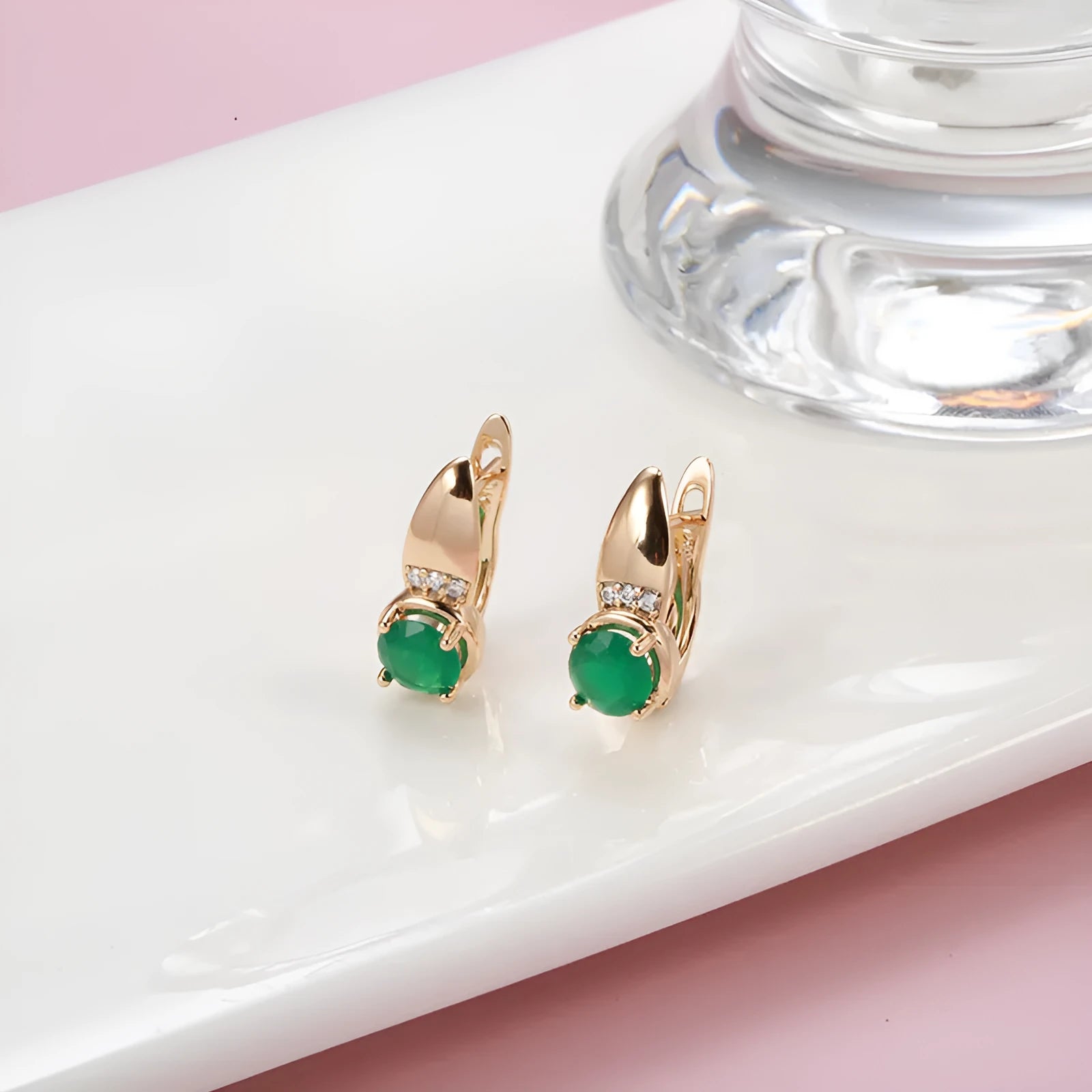 Rose gold plated copper stud earrings with emerald green zircon stone in U-shaped retro design on white background