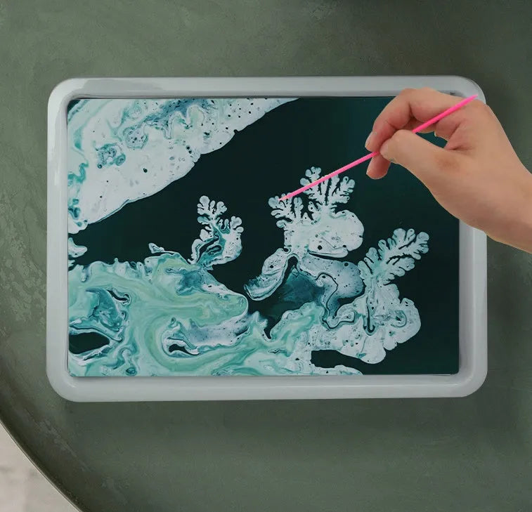 Hand painted doodle educational toy set with gouache paints, concentrated liquid, stirring rods, and drawing paper on a table