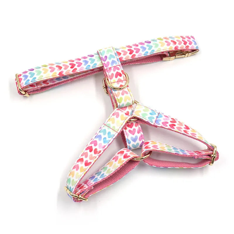 Pink colourful dog chest and back harness with gold buckle and heart-shaped stone details.