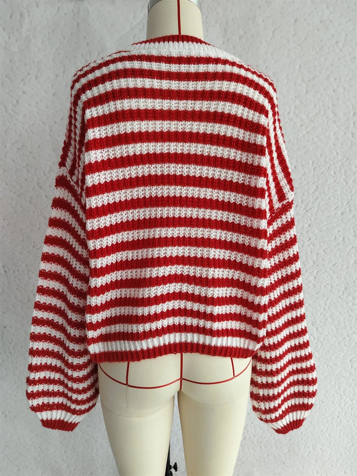 Woman wearing a black and white striped loose pullover sweater with a round neck and long sleeves.