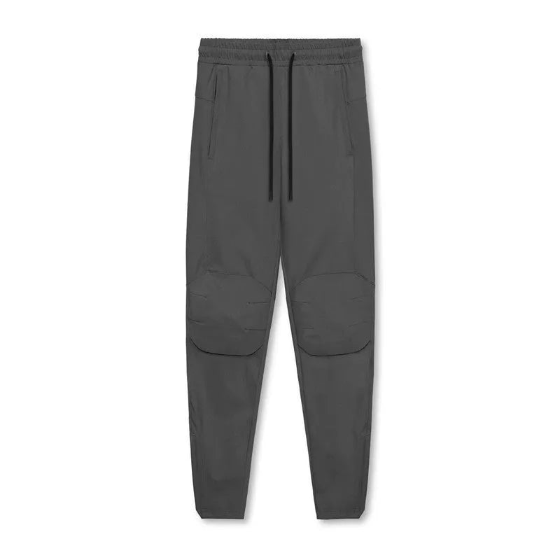 Male model wearing dark grey loose-fit fitness trousers with ankle ties.