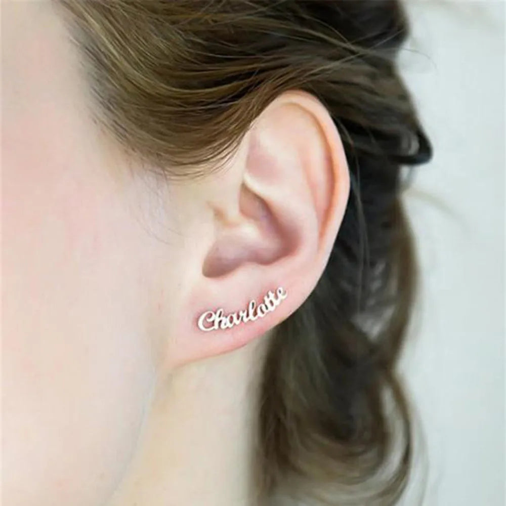 Custom English letter name earrings in rose golden finish on a plain background