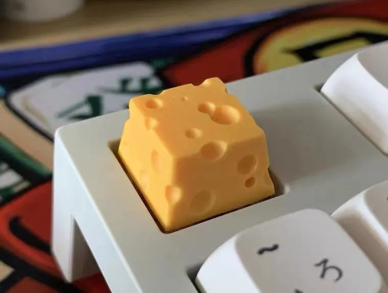 Yellow resin mechanical keyboard keycap sculpted like a wedge of Swiss cheese.