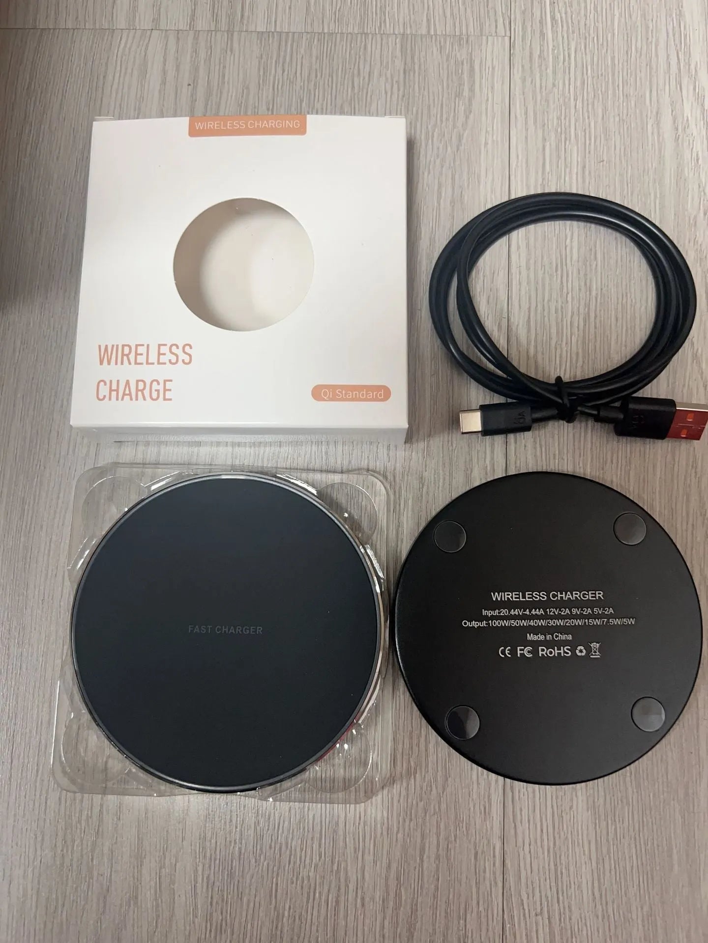 Black 15W fast wireless charger pad with type C cable on a desk