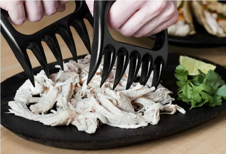 Two black bear claw meat shredders for BBQ preparation on a kitchen counter.