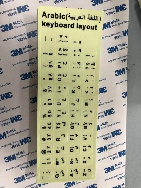 Glowing yellow multilingual keyboard stickers showing Arabic, Thai, Hebrew, French, Italian and German characters