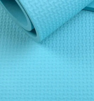 Red EVA yoga mat showing thickness, next to a blue mat, on a wooden floor.