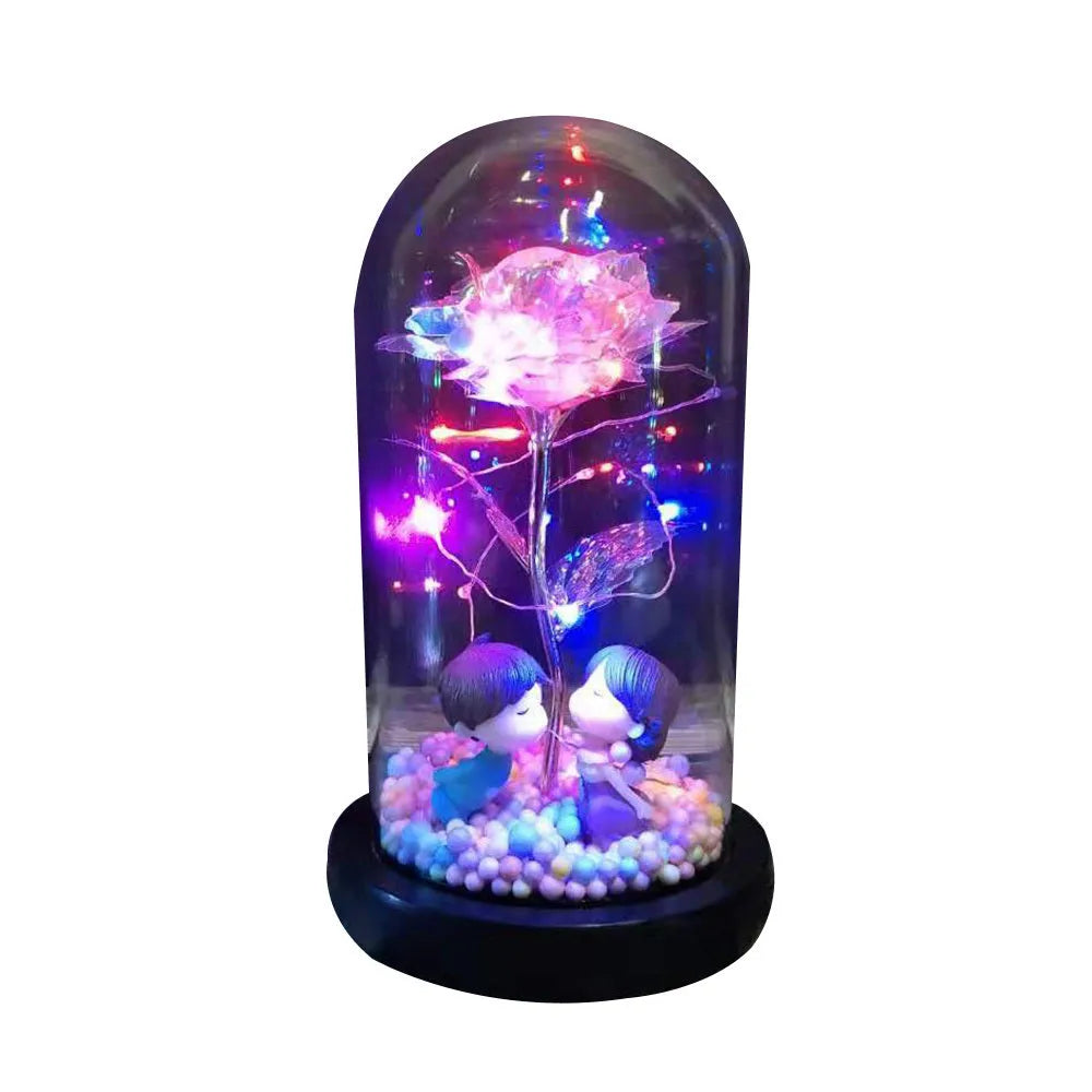 Artificial gold rose in clear glass dome on black base with LED lights for home decor