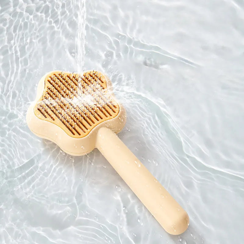 Green and yellow handled self-cleaning pet grooming comb with stainless steel needle bristles.