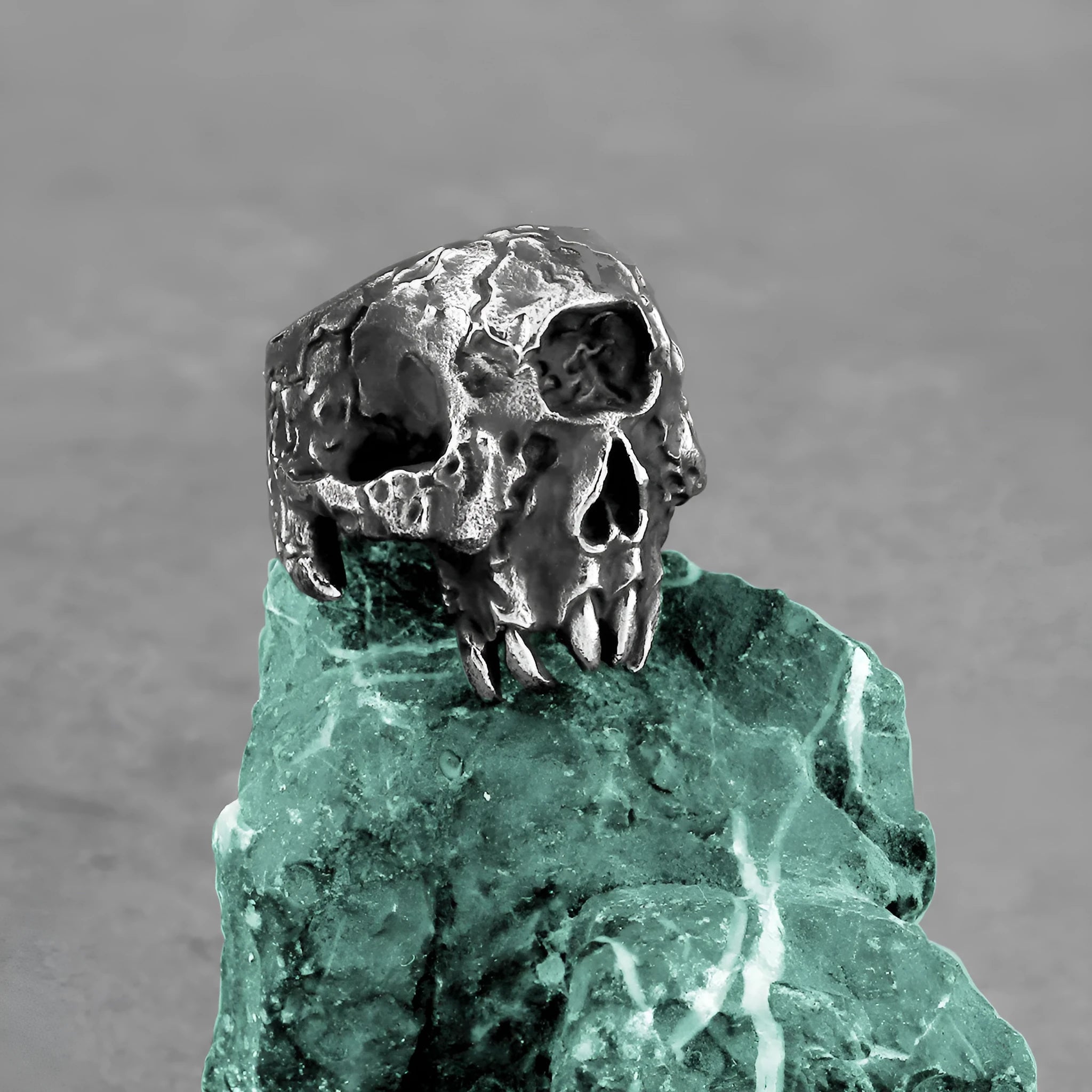 A close-up of a silver-toned alloy ring featuring a detailed one-eyed skull design.