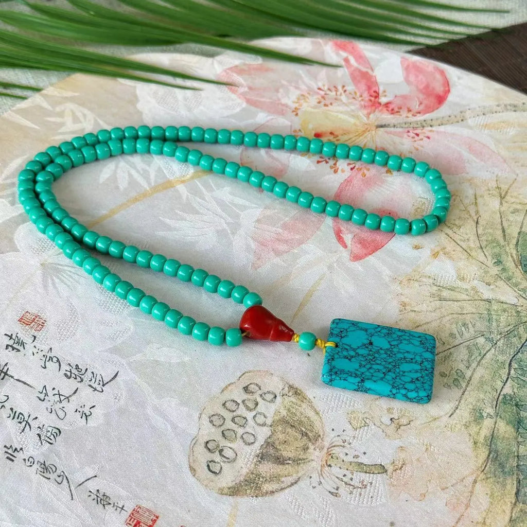Turquoise ball bead necklace with a hand-woven mesh flower lucky pendant in stone.