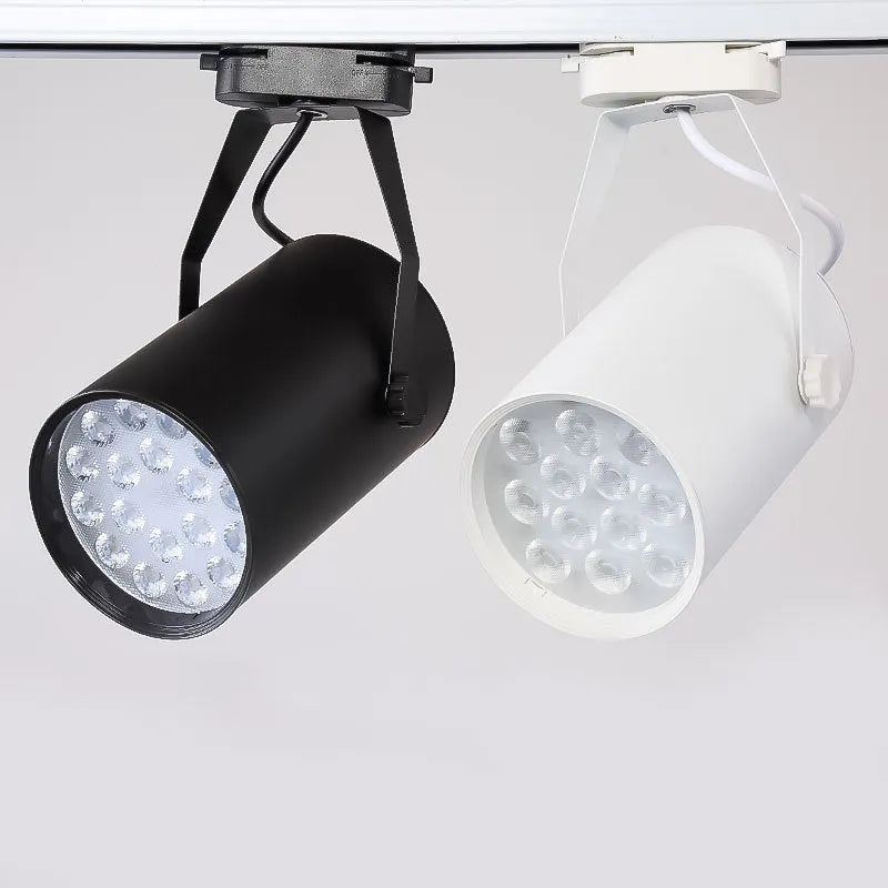 Black and white aluminium LED track spotlight on a lighting track, aimed at a display.