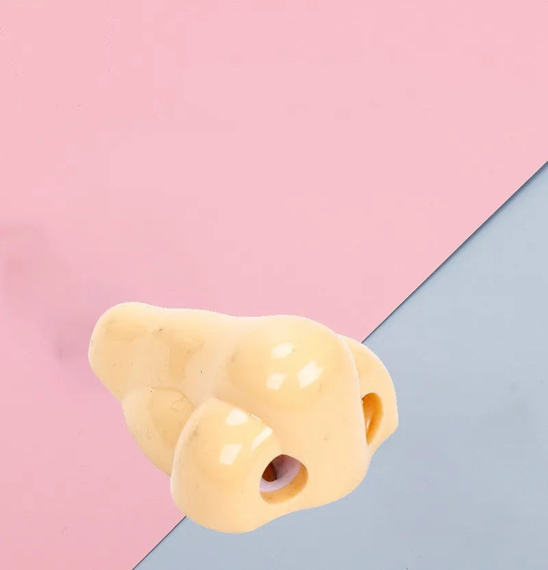 Flesh-coloured plastic pencil sharpener with large nostril and geometric shape on a white background.