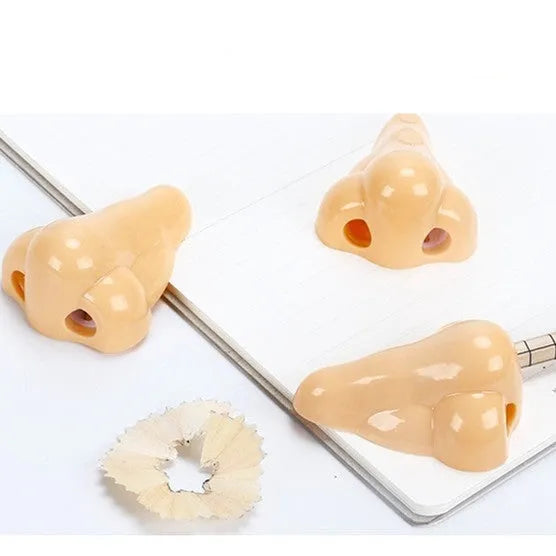 Flesh-coloured plastic pencil sharpener with large nostril and geometric shape on a white background.