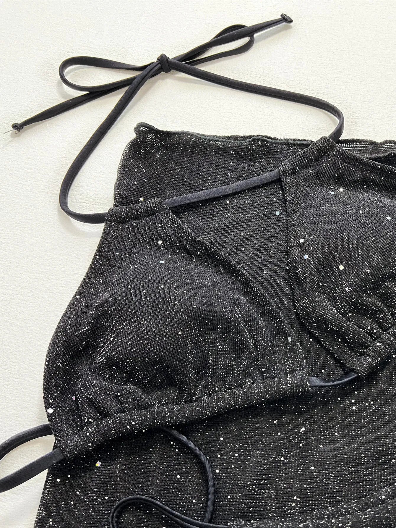 Black three-piece bikini swimsuit set with matching top and shorts on white background