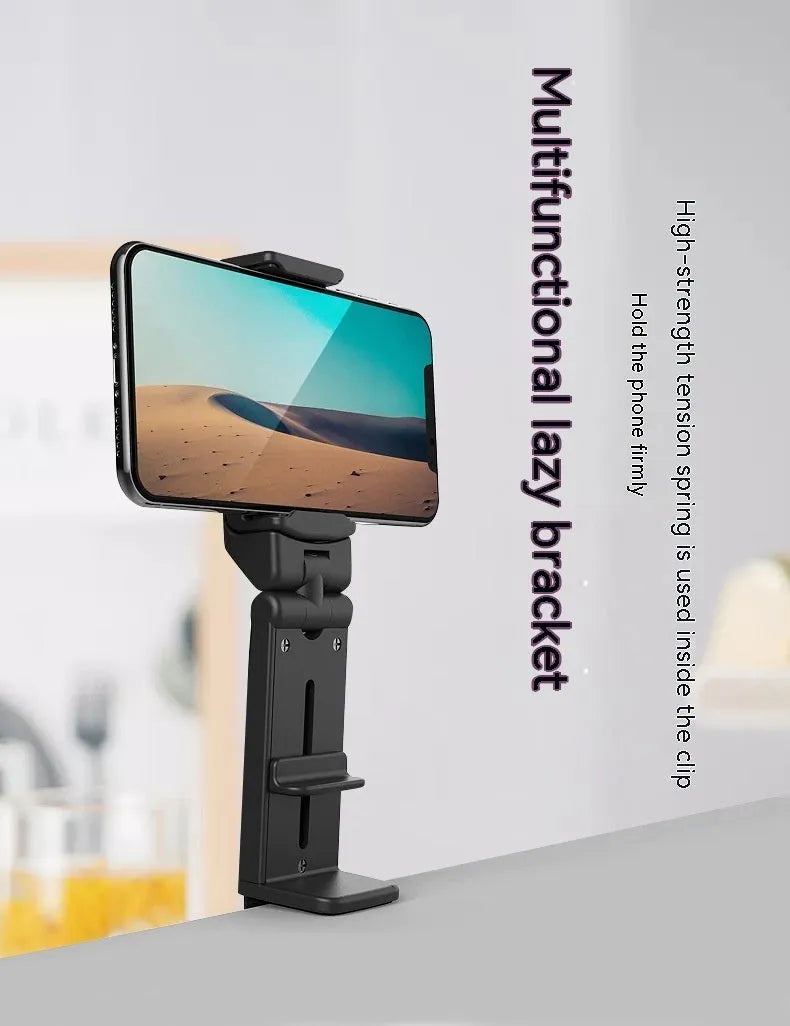 Black foldable ABS phone holder with 360-degree rotation on a desk next to a smartphone