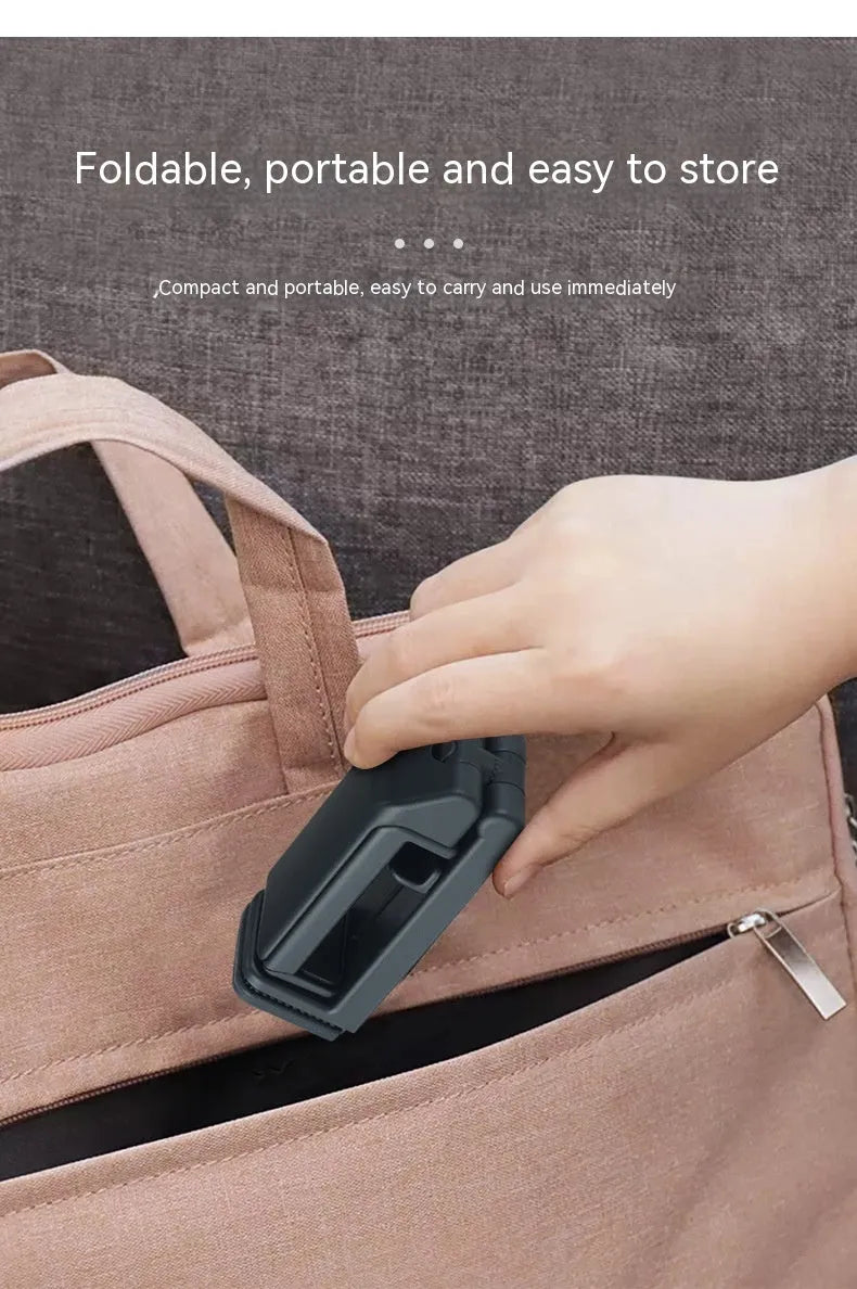 Black foldable ABS phone holder with 360-degree rotation on a desk next to a smartphone