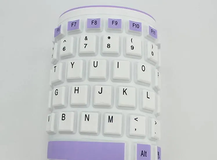 Folding silicone keyboard in pink with USB cable, placed on a desk