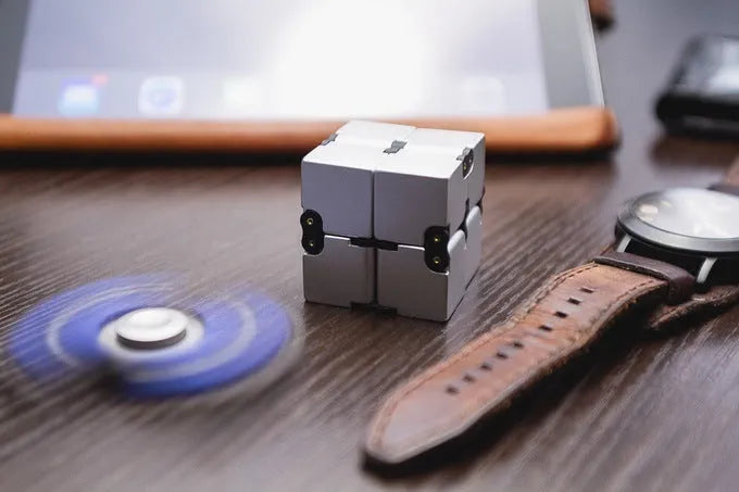 Zinc alloy infinity cube fidget toy showing black and silver rotating cube puzzle on a desk.