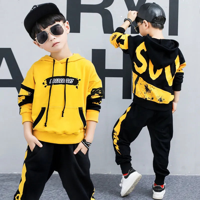 A boy wearing a black Korean-style hooded cotton tracksuit set with a letter print, featuring long sleeves and matching trousers.