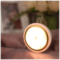 Circular white motion sensor LED light with a compact design, shown mounted on a wall.